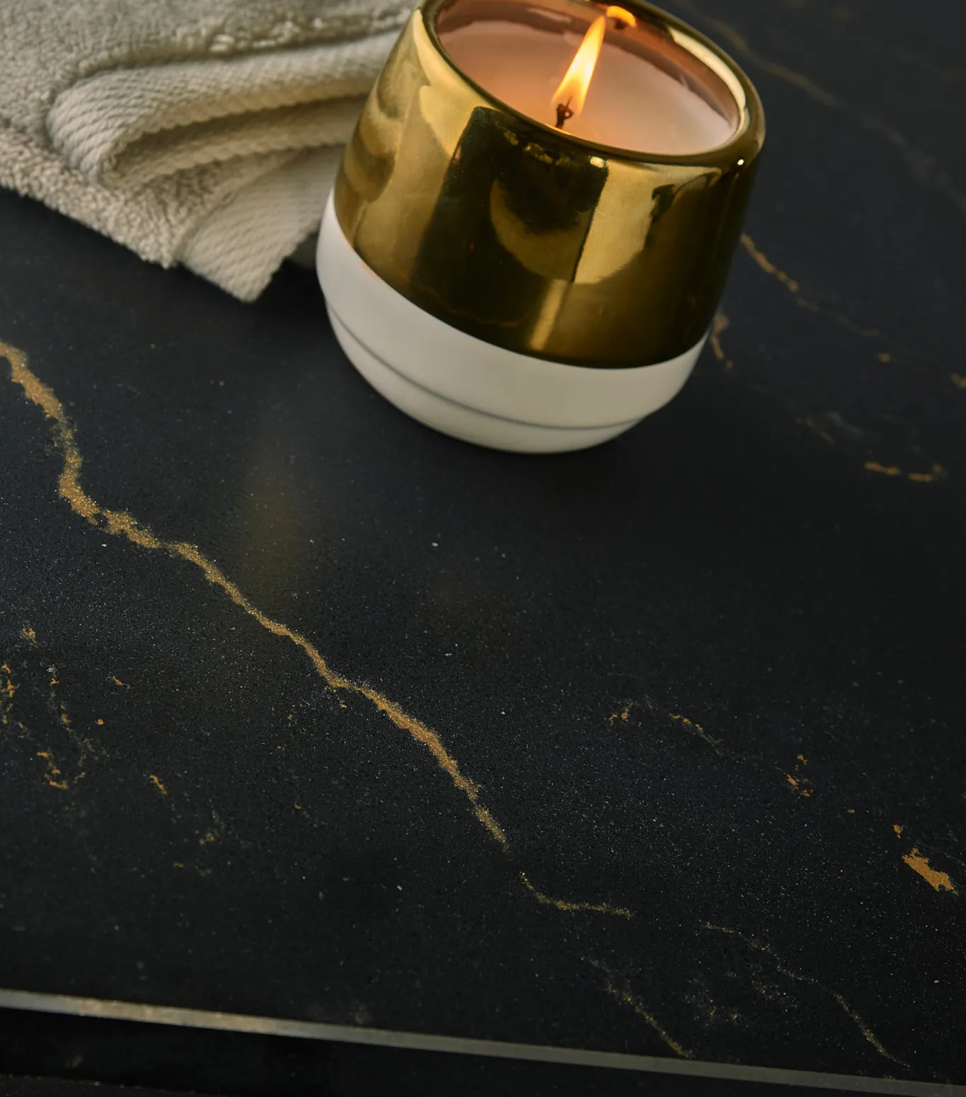 a detailed view of Cambria Quartz Woodcroft countertop with a burning candle and towel on top.