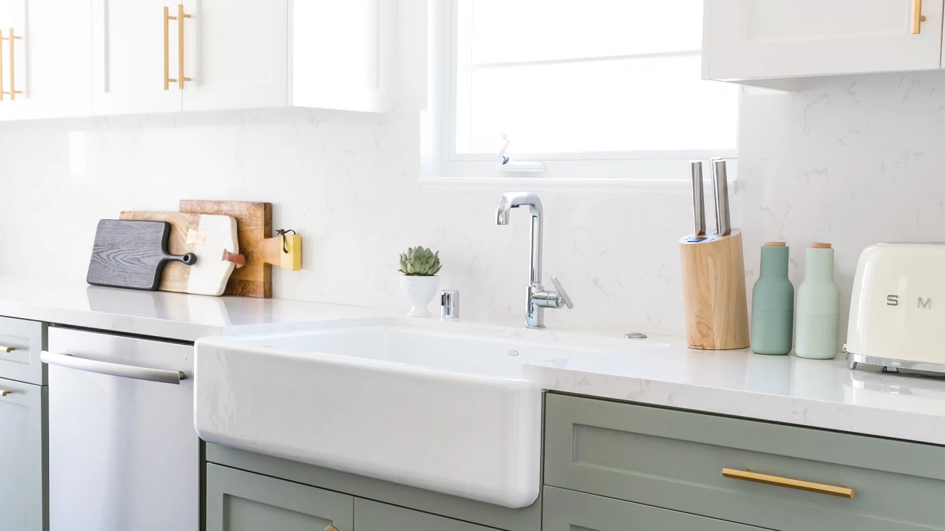 a two toned kitchen with marble-like Torquay quartz countertop and backsplash with sage green cabinets