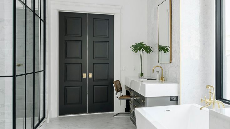 a white bathroom with two Swanbridge quartz vanities with a large white bathtub and brown French doors