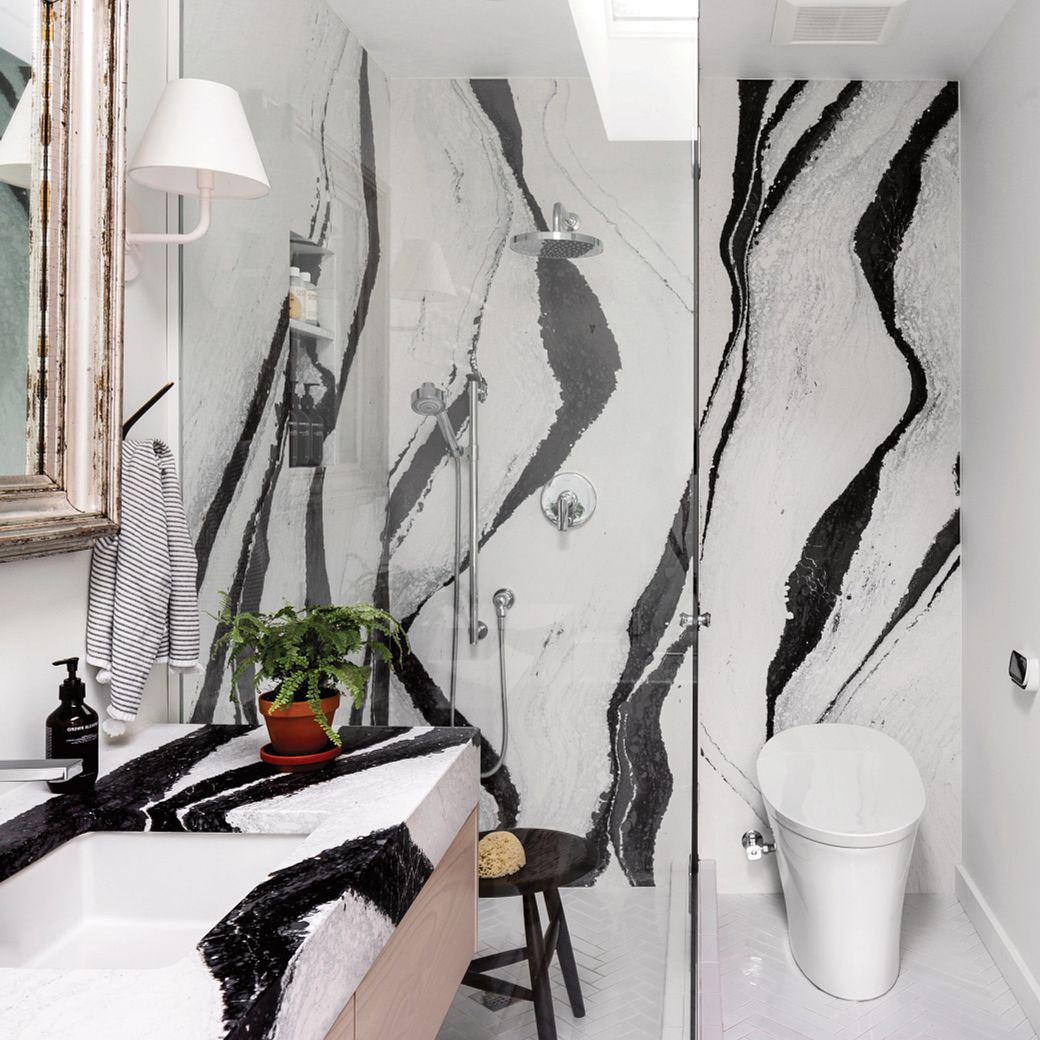 a Scandinavian style bathroom with Cambria Bentley shower surround and matching Bentley quartz countertops paired with a modern stool and modern glass shower door.
