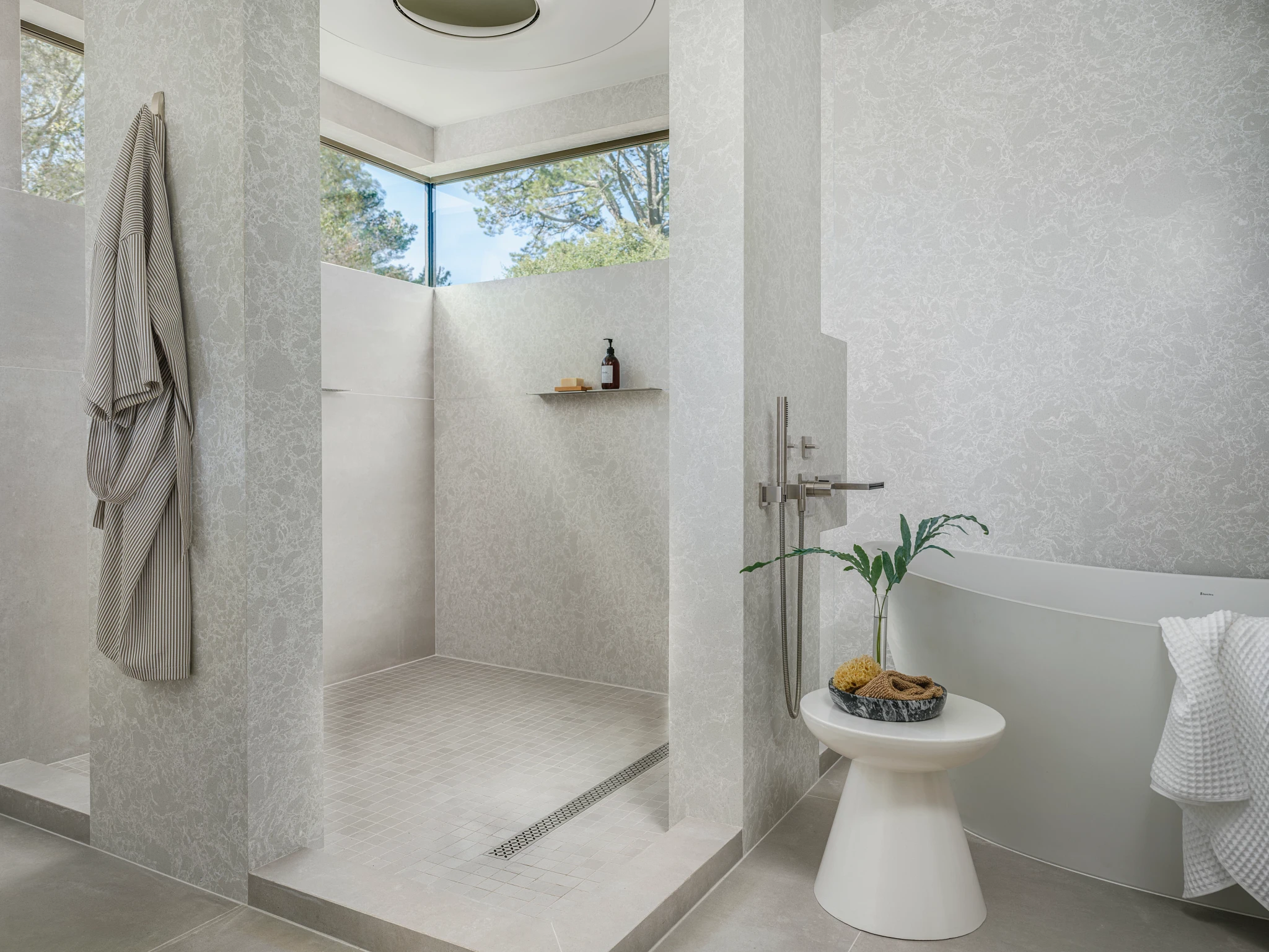 a natural and clean bathroom with a large, open shower with windows, a spot to hang a rob, and made from Cambria quartz Big Sur Mist with complementary Big Sur Mist walls.