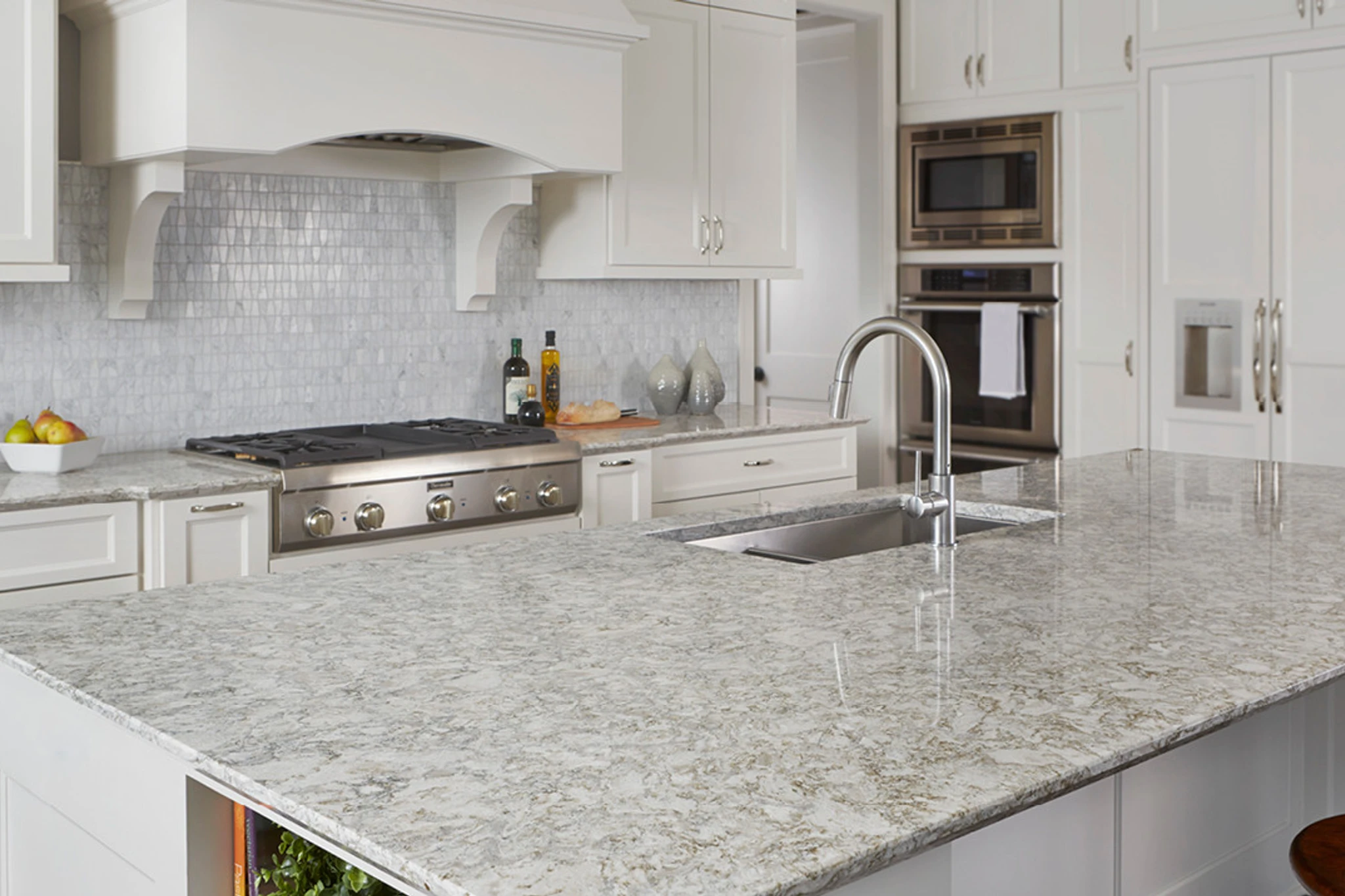 a clean, traditional kitchen with Cambria Berwyn quartz countertops, a center island with Berywn countertops and a sink, a gorgeous range and hood, and white cabinets. 