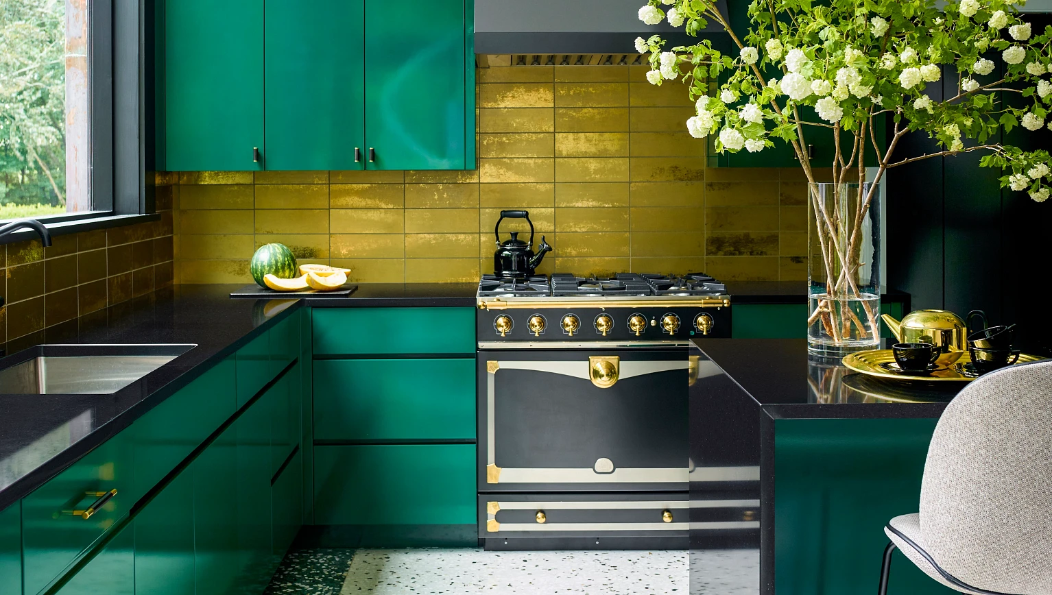 Kitchen with chrome green cabinets, a gold tile backsplash and black quartz countertops
