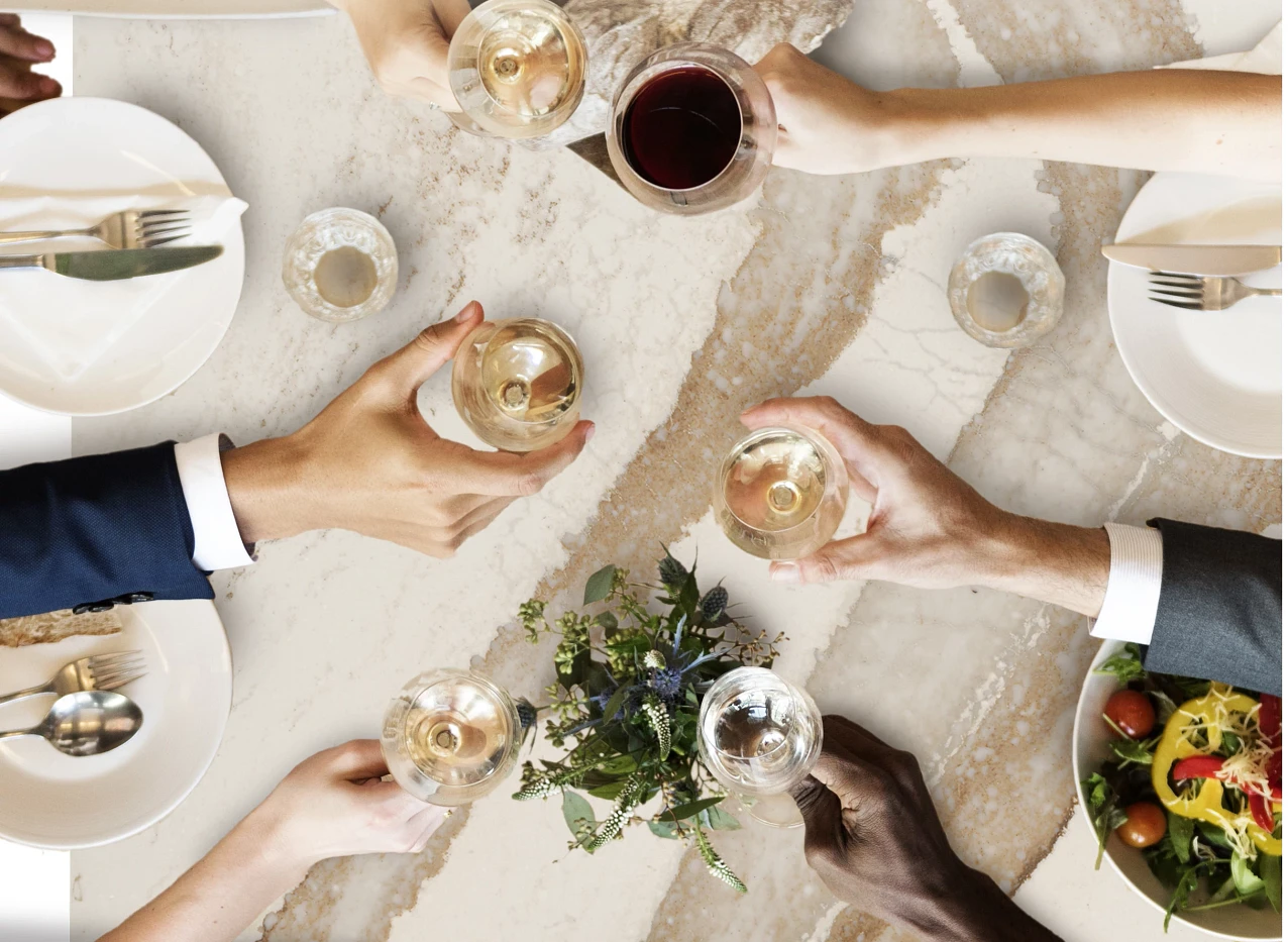 hands around a quartz countertop sharing a meal and drinks together.