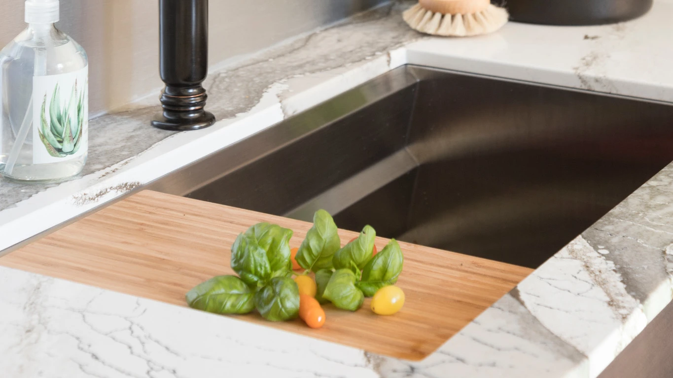 a sink with a small cutting board with white and gray Skara Brae quartz countertops