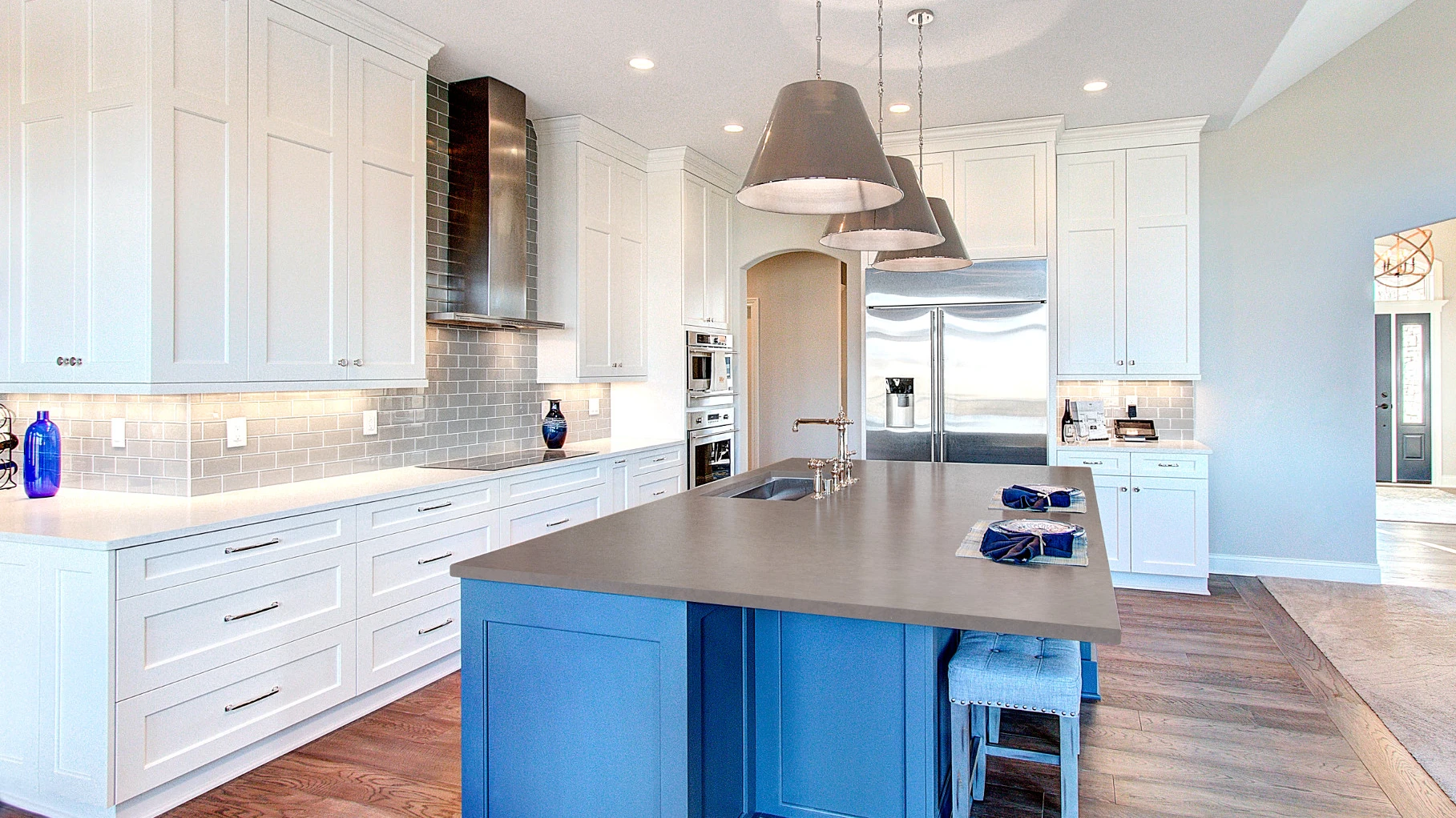 A stunning white kitchen from Anderson Homes with blue center island topped with a gray quartz countertop made from Cambria Carrick Matte.