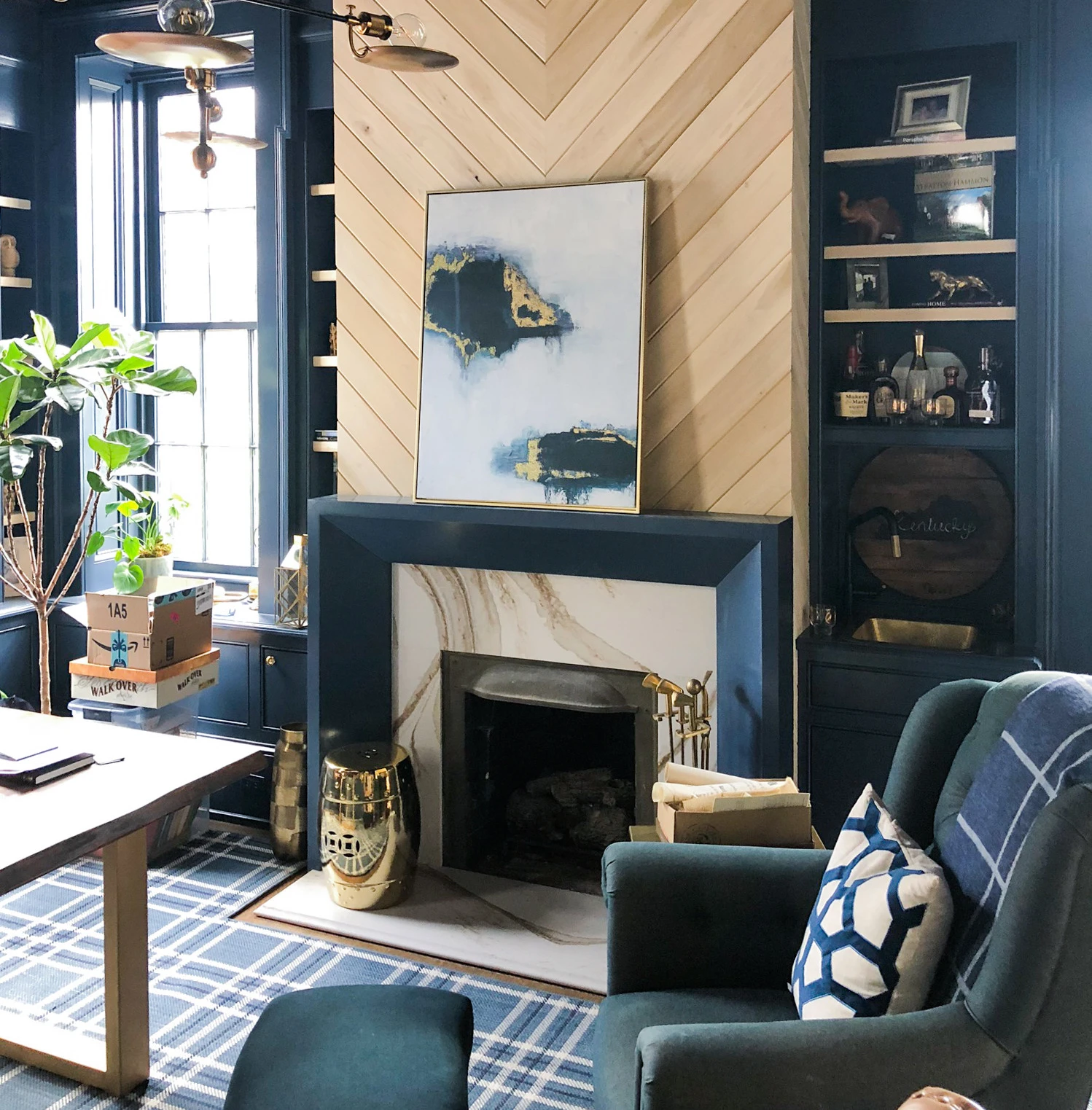 a dark blue and green sitting area with a large wooden detailed fireplace and Cambria Brittanicca Gold Warm fireplace surround