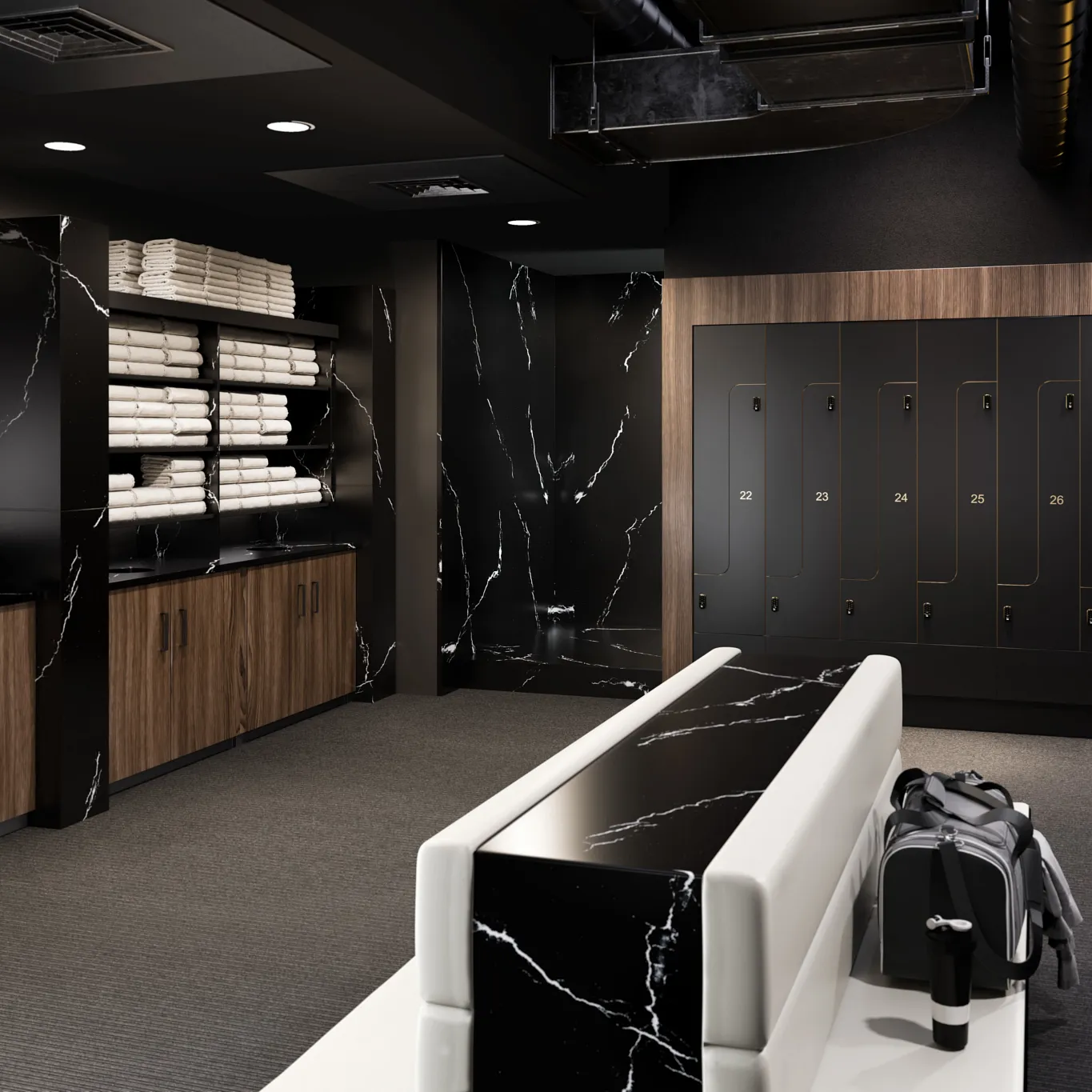 a modern fitness studio locker room with black numbered lockers, Cambria Blackbrook quartz wall accents, a shelf with towels, two couches back-to-back.