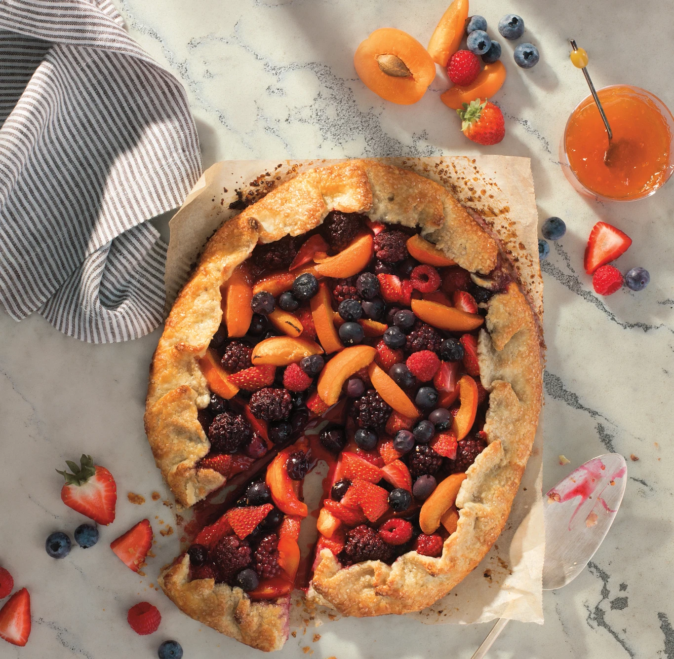 a strawberry, blueberry, and peach pie with one slice cut out sitting on top of Cambria's Berkshire Steel Sculpted quartz countertop.