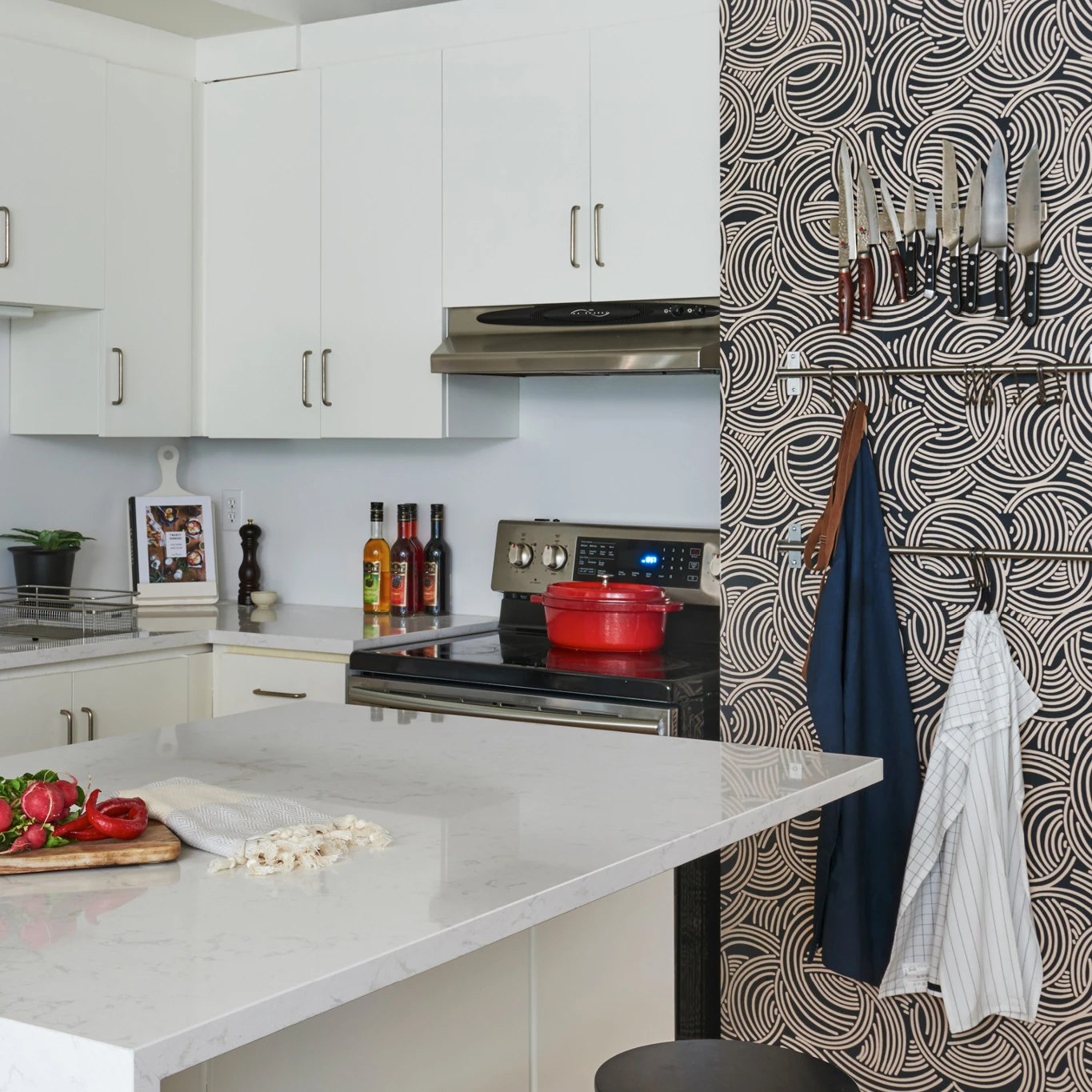 a white kitchen with a printed statement wall with added extra storage for knifes and aprons