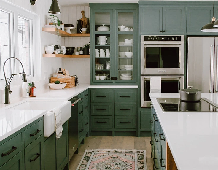 Kitchen with sage green cabinets, white quartz countertops, a farmhouse sing and white walls.