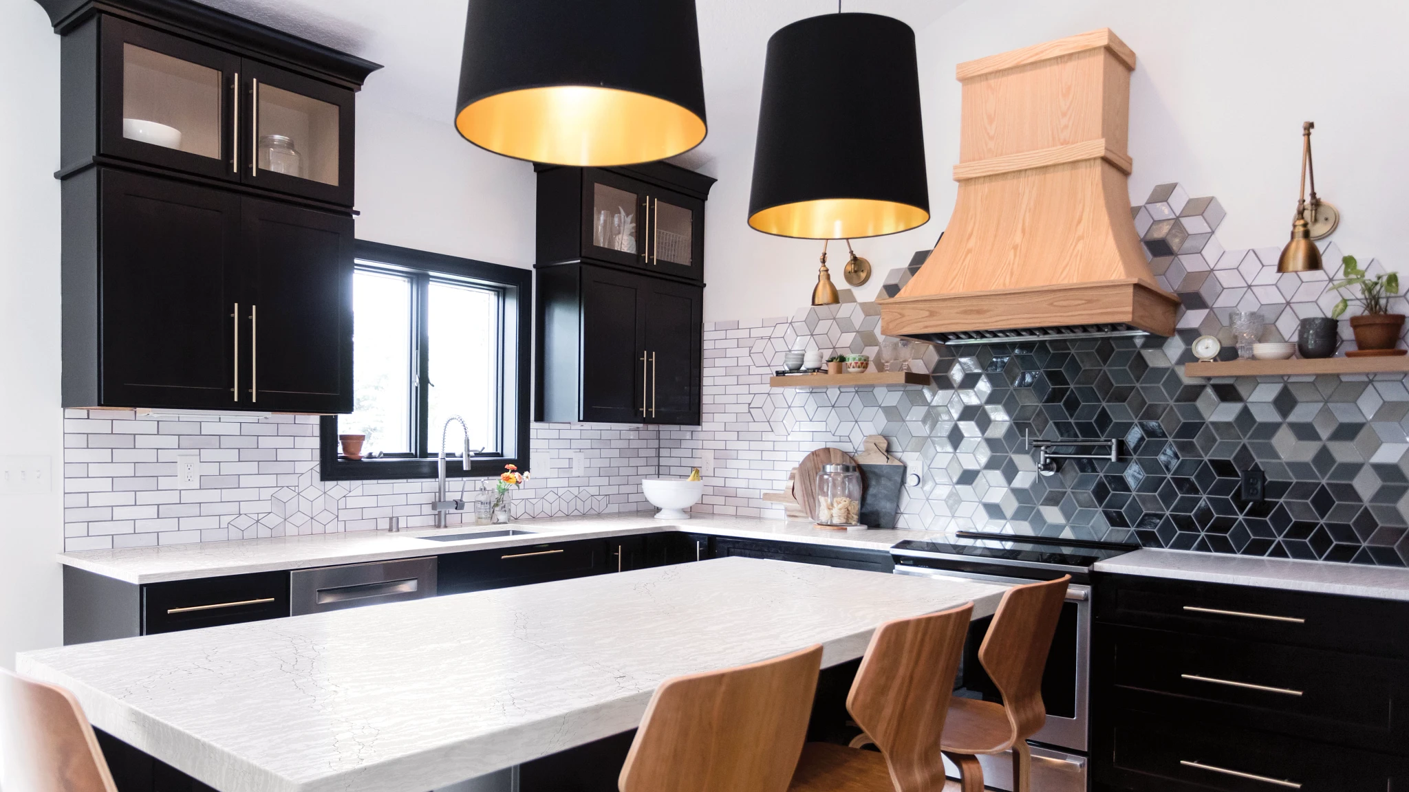 a bold kitchen with black and white cubical tiled backsplash as well as white subway tile, with black upper and lower cabinets, white quartz countertops, a small island, wooden hood over the range, and wooden bar stools